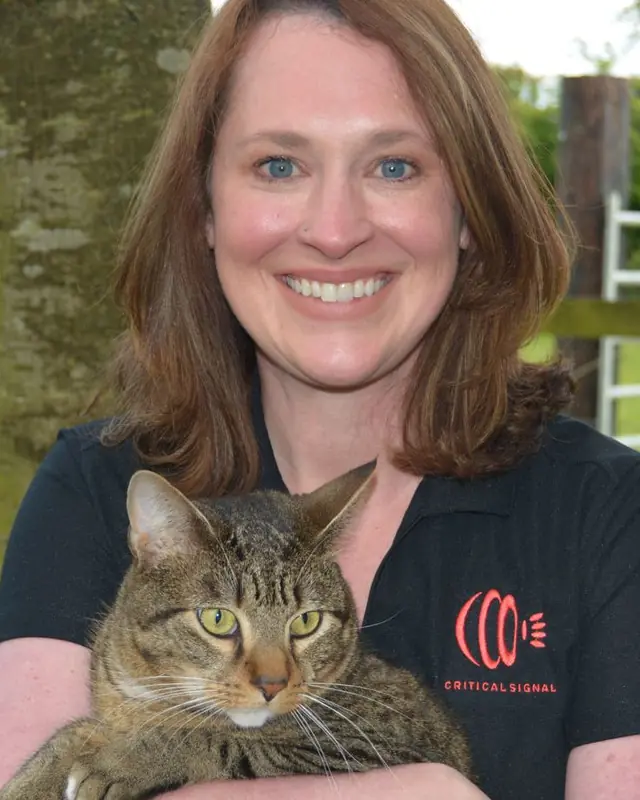 Erin Daniels outdoors holding a tabby cat.